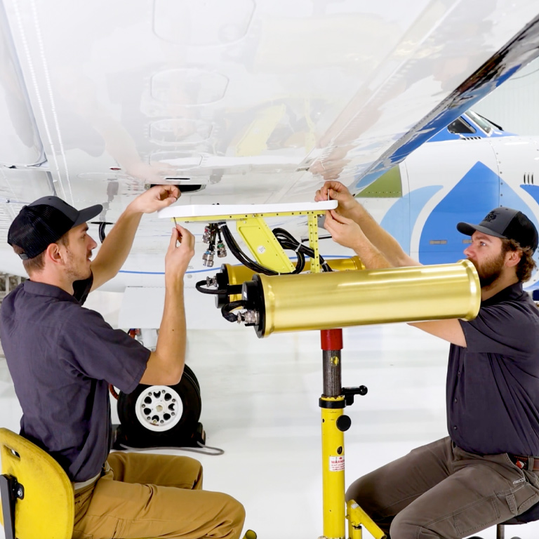 Two SPEC technicians install atmospheric research instruments on a wing